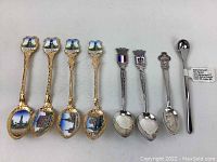 Eight collectible teaspoons displayed showing variety in handle designs and finish.
