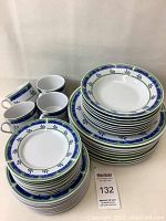Full view of the stacked dishes and cups showing the pattern and quantity of items.