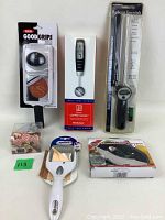 Photo showing 5 of the 6 new kitchen items in their original packaging: OXO Good Grips gripper, Brooders coffee scoop, BBQ meat thermometer, meat chopper, and vegetable peeler.