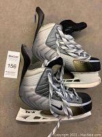 Pair of gray, black, and white Nike ice hockey skates showing overall external condition, laces tied, with visible wear.
