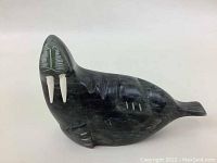 Side view of the polished dark green soapstone walrus sculpture showing its profile, tusks, and carved details.