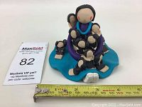 Front angle view of the signed Native American storyteller clay figurine with a ruler for scale showing approximately 4 inches width.