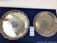 Two silver plated trays placed side by side on a table, showing condition and size difference