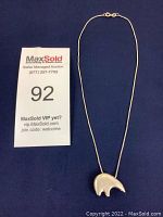 Sterling silver necklace with a solid polar bear pendant placed on blue fabric, shown fully extended with clasp visible.
