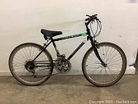 Full side view of the black Triumph Ravine youth bicycle showing 24-inch wheels, seat, frame and handlebar.