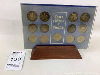 Blue framed acrylic display of 7 Canadian commemorative coins featuring Coats of Arms of Canada, with wooden base