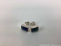 Pair of square-shaped vintage sterling silver stud earrings with blue-green colorful stone inlays shown on a white surface.