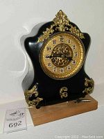 Front view of black curved case with gold ornamental bezel and dial