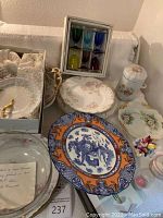 Overview of assorted porcelain plates, colored crystal glasses, decorative porcelain container, and bowls