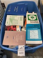 Blue plastic tub filled with assorted science books including Radiobiology and Energy Resources, Plutonium Chemistry and Transuranic Speciation in Aquatic Environment