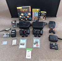 Full view of all items in the lot arranged on floor with cases, books, camera and small optics