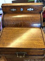 Front view of oak roll-top desk closed showing drop-down shelf and calendar