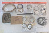 Full lot of various silver wire coils, ring sizers, and tools arranged on a white surface with a ruler for scale.