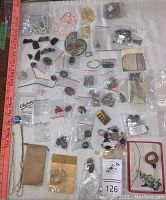 Top-down overview of stones, chains, and jewelry components arranged on a surface including small baggies and pouches