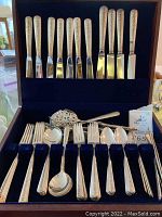 View of all pieces in velvet-lined wooden box, top row of knives and bottom compartments with forks, spoons, spreaders