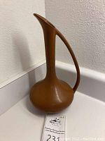 Full view of camel brown Van Briggle pottery pitcher showing narrow neck, curved handle, and rounded base.