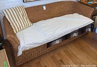 Front view of wicker sofa with sheet-covered seat and striped pillow