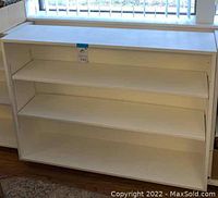Front view of white wooden rolling shelf showing three open shelves and smooth white finish.