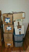Stack of cardboard boxes and plastic bins containing yarn and fabric