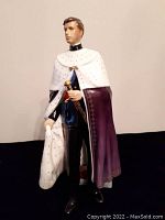 Front angle full view of the Prince Charles Royal Doulton figurine showing full cloak with white and purple detailing and sword.