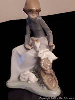 Front angled view of the NAO by Lladro porcelain girl figurine holding rabbits, showing detail of dress, hair, and animal figures.