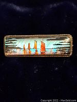 Full view of the rectangular pin showing the glass front with the design of orange sailboats on a blue background.