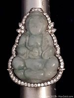 Front view showing carved jade Buddha figure surrounded by clear stones set in silver