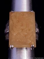 Top view showing rectangular yellow jade stone with carved details set in sterling silver prong setting.
