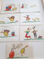 Full view of the 7 hand-painted watercolor Easter artworks arranged on a white surface.