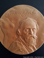 Front close-up photo of ceramic sculpture plaque showing elderly man's bust with mustache and cap, with faint signature at top.