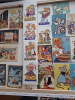Photo of 21 colorful vintage Russian postcards laid out on a flat surface showing various folk art style characters and scenes.
