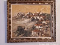 Full view of framed oil painting showing a hillside village and ornate gilt frame