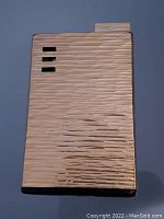 Front view of Ronson electric lighter showing textured metal surface with three rectangular cutouts.