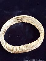 Top-down view of sterling silver mesh bangle on black background