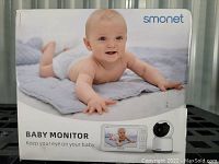 Front view of the Smonet Baby Monitor box showing a baby and the monitor device.