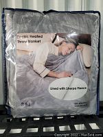 Front image of the packaged Microplush electric heated throw blanket, showing product image and key features including sherpa fleece lining.