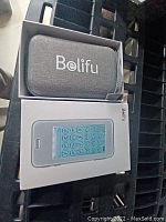 Gray fabric carrying case with Belifu logo and white device box showing screen interface.