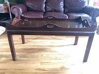 Front view of wooden Butler's coffee table with removable tray top and handles visible, some surface scratches