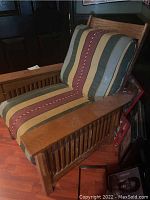 Side angle showing wooden frame with slatted sides and striped upholstered cushions in muted tones.