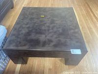 Top view showing the square lacquer coffee table with scratches on the surface and wood floor background.