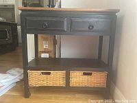 Front view of console table showing two drawers with ring handles, lower shelf and wicker baskets below.