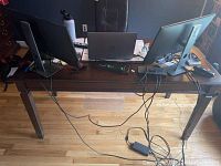 Wooden desk with drawer, shown with laptops and monitors on top and visible cables, highlighting the desk surface and drawer front.