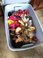 Blue plastic tote containing multiple vintage and collectible dolls, including fabric dolls with black hair and colorful clothing.