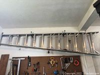Full view of ladder mounted horizontally on garage wall among tools