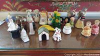 Front view of the novelty salt and pepper shakers arranged on a wooden surface, showing a variety of animal shapes, storybook characters, and colorful designs.