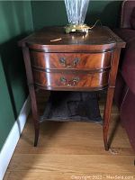 Front view of one side table highlighting its two drawers, curved legs and wood grain finish.
