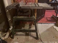 Front left angle view of Skilsaw table saw on metal stand showing control panel, blade slot, and bench surface with ventilation holes.