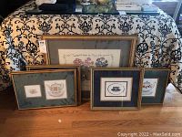 Five framed prints arranged on floor, floral and tea cup themed artwork, visible water damage