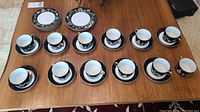 Full view of set including 15 tea cups, 15 saucers, and 2 salad plates arranged on a wood surface