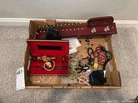 Photo showing the assortment of bead necklaces, costume jewelry, wooden tie rack and Timex watch in a cardboard box.